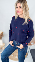 Détail broderie coeurs rouges sur pull bleu marine col rond taille unique