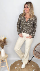 Femme portant une chemise kaki à fleurs blanches et un pantalon blanc - La Boutique de Lydie.