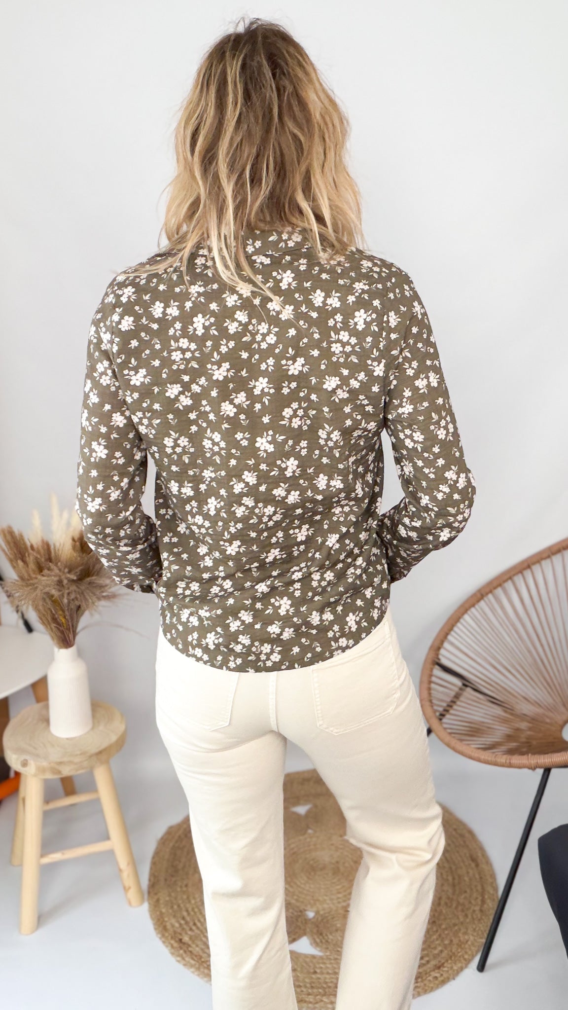 Femme portant une chemise kaki à fleurs blanches et un pantalon blanc - La Boutique de Lydie.