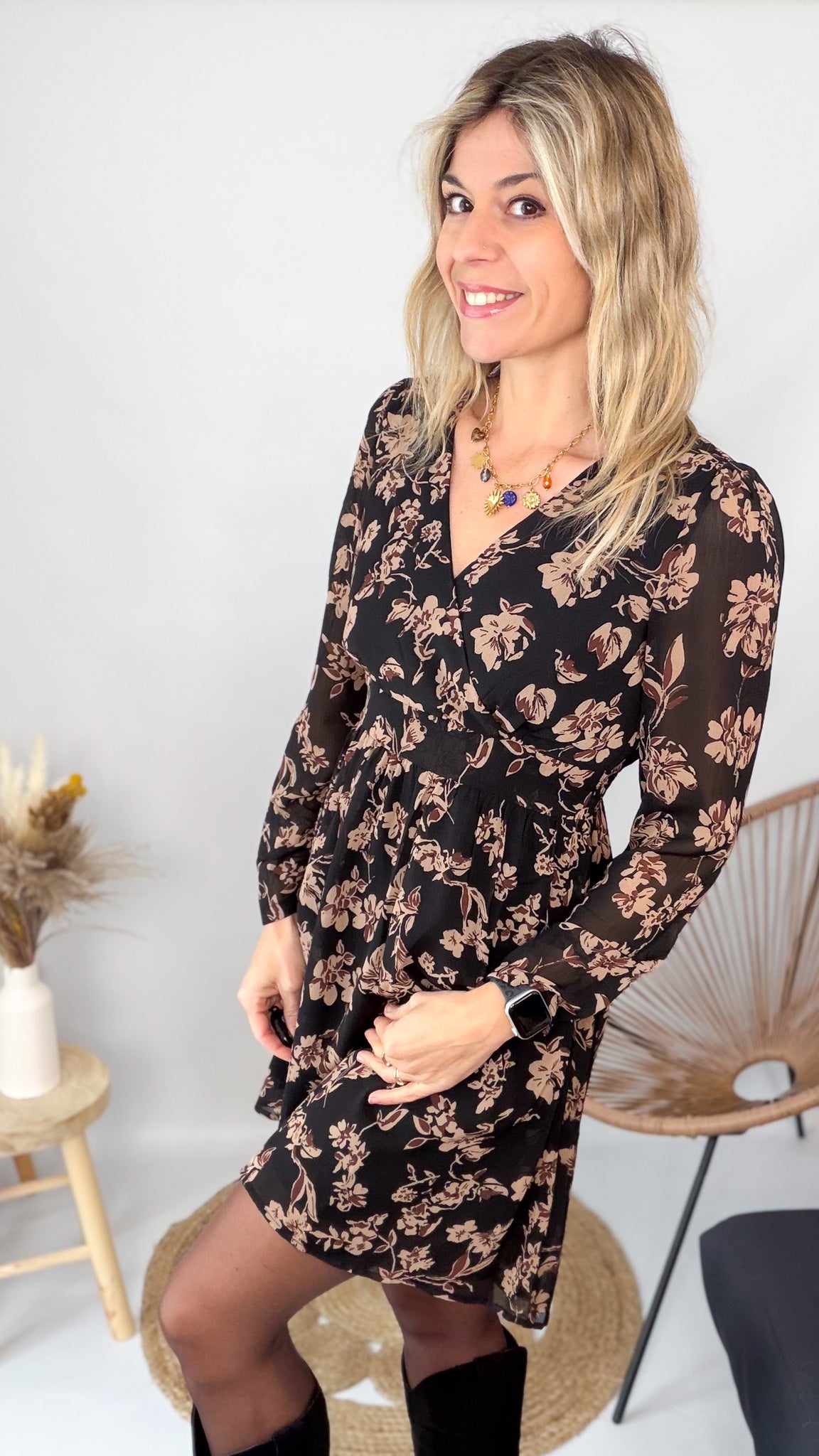 Femme portant une robe noire courte à fleurs avec des bottes noires - Prêt-à-porter La Boutique de Lydie.