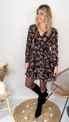 Femme portant une robe noire courte à fleurs avec des bottes noires - Prêt-à-porter La Boutique de Lydie.