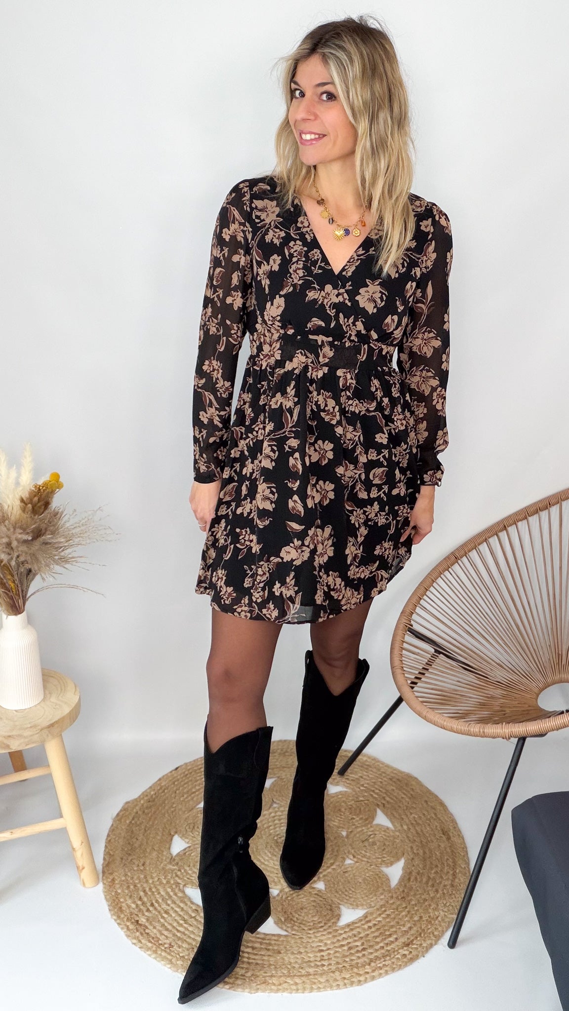Femme portant une robe noire courte à fleurs avec des bottes noires - Prêt-à-porter La Boutique de Lydie.