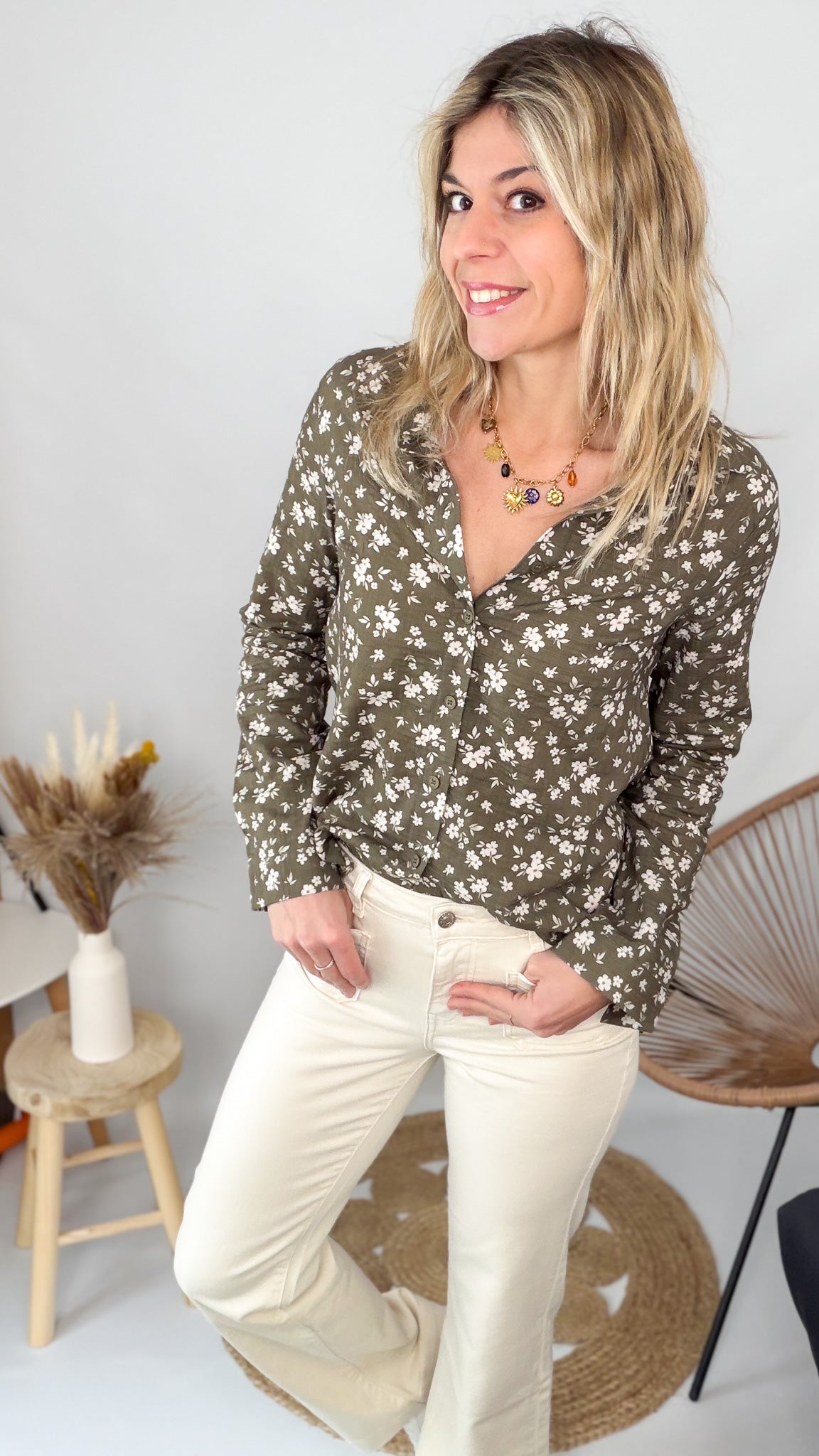 Femme portant une chemise kaki à fleurs blanches et un pantalon blanc - La Boutique de Lydie.