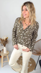 Femme portant une chemise kaki à fleurs blanches et un pantalon blanc - La Boutique de Lydie.