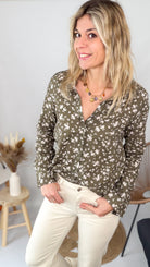 Femme portant une chemise kaki à fleurs blanches et un pantalon blanc - La Boutique de Lydie.