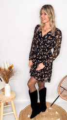 Robe noire fleurie 100% polyester, coupe fluide, portée avec des collants et des bottines.